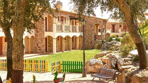 A courtyard with stone buildings, a colorful fence, and playground equipment. - Hapimag Resort Mas Nou (Castell-Platja d'Aro)