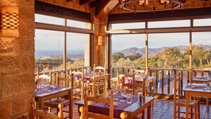 A restaurant with wooden furniture and large windows offering mountain views. - Hapimag Resort Mas Nou (Castell-Platja d'Aro)