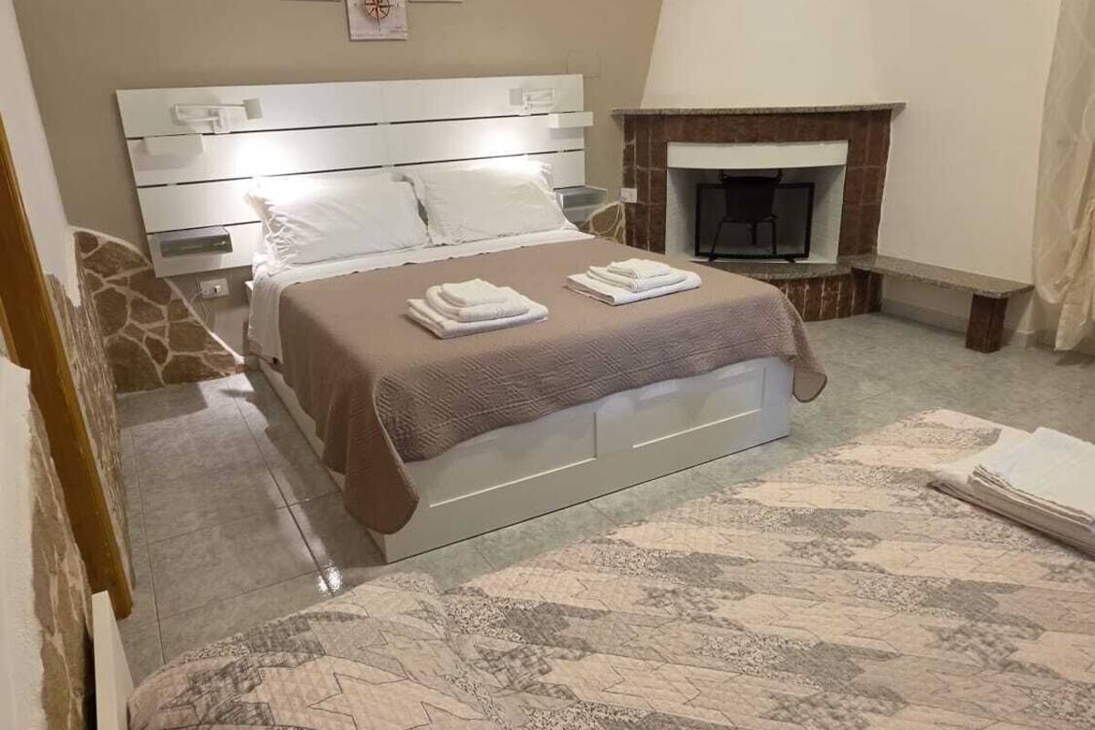 A bedroom with a bed, a fireplace, and wall art.