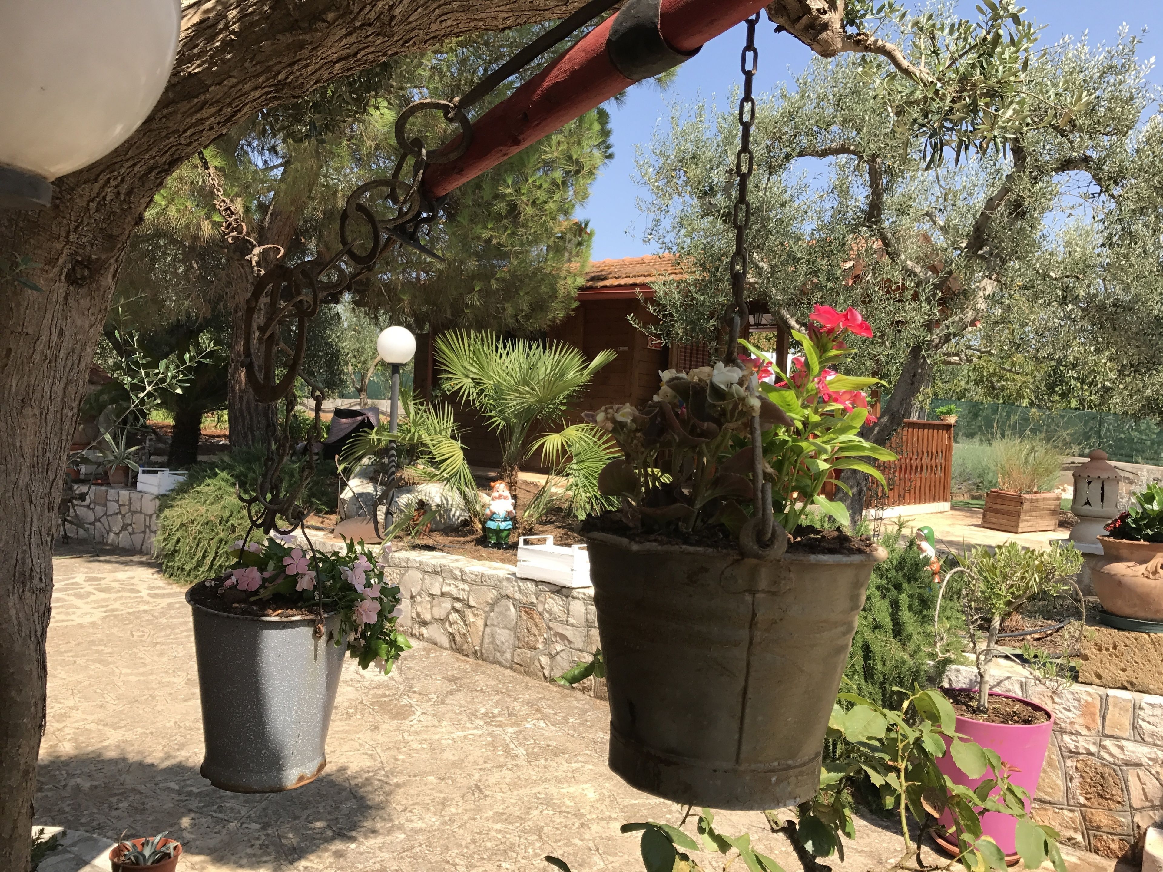 Ein Garten mit Blumentöpfen, einer Steinmauer und einem rustikalen Zaun.