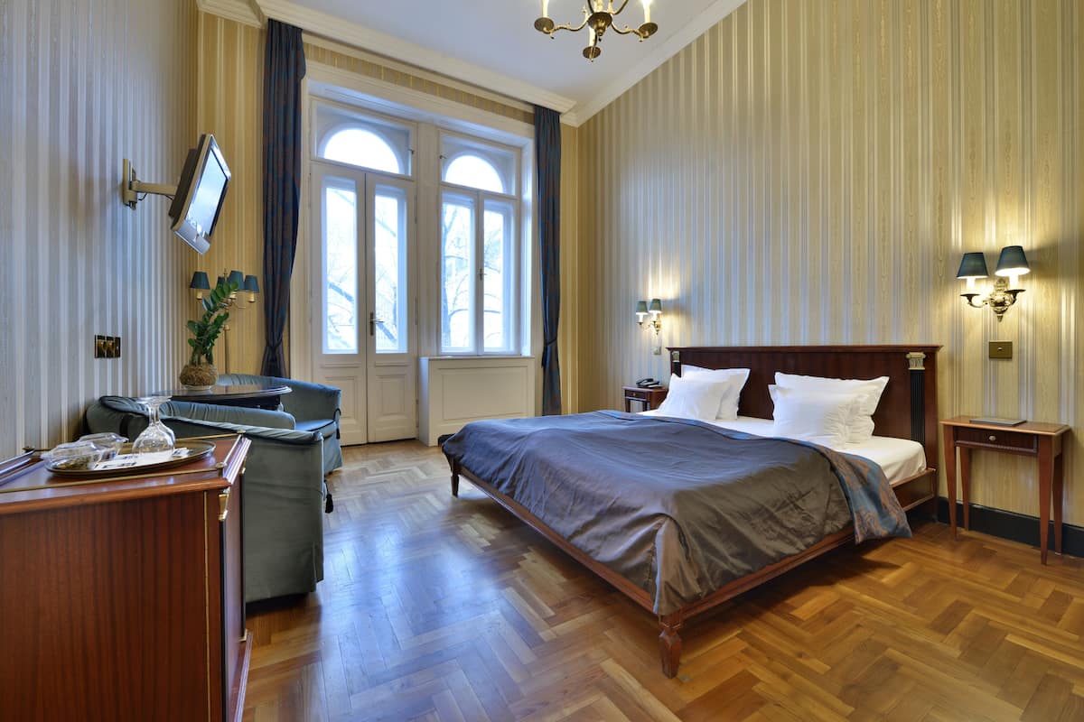 A hotel room with a wooden bed, a desk, a television, and a window with curtains.