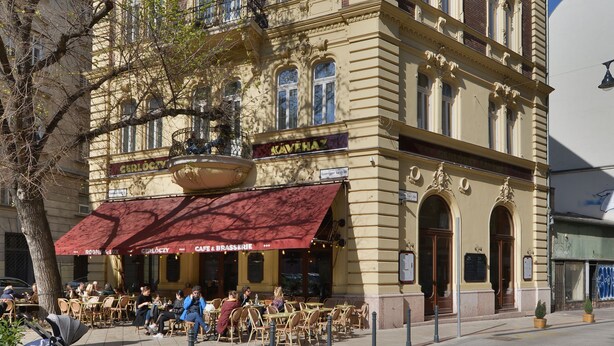 A historic building with a cafe on the ground floor, outdoor seating, and a clear blue sky. - Gerlóczy Boutique Hotel (Budapest)