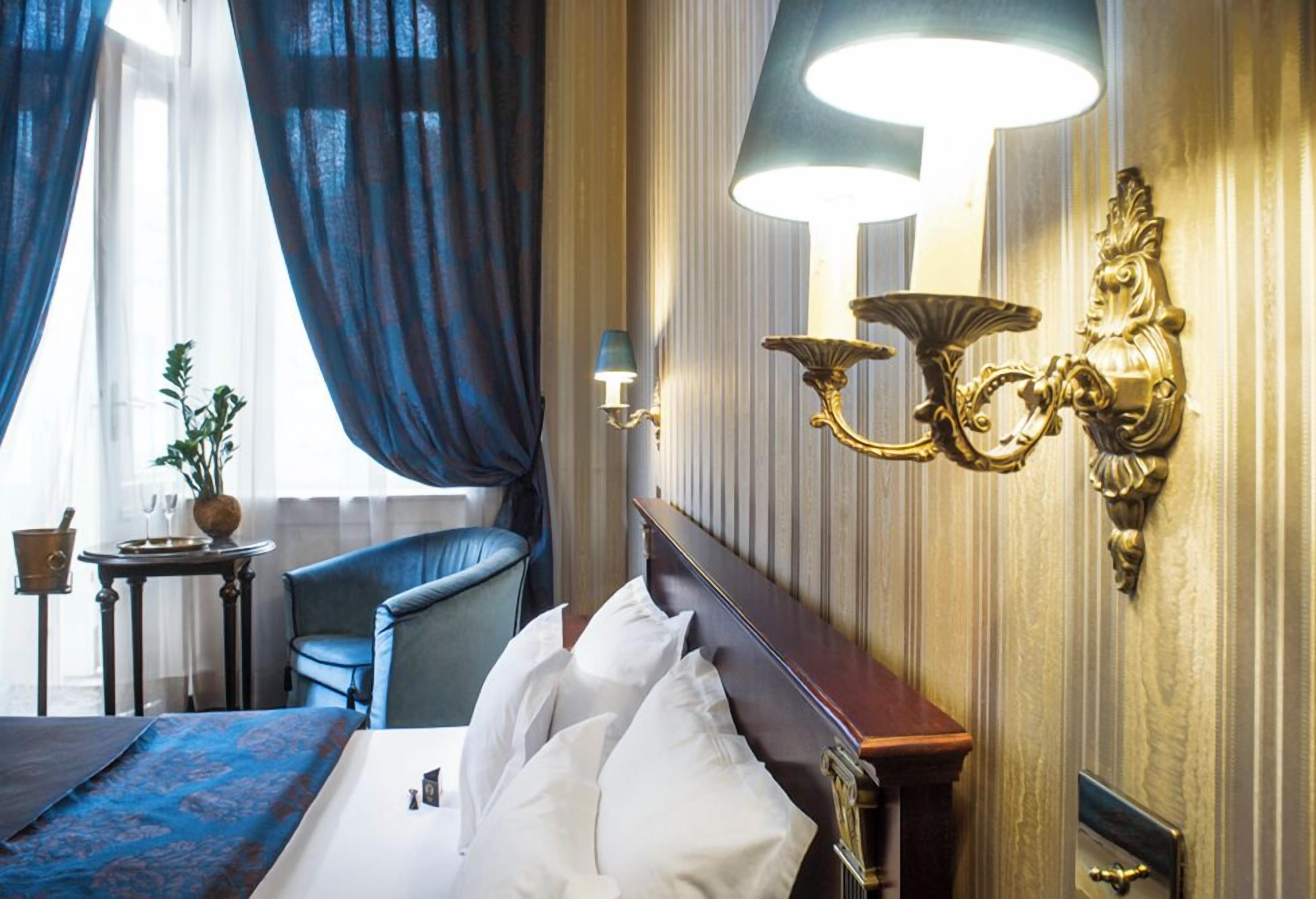 Una habitación de hotel con cama, una silla, una lámpara y una mesita con una planta.