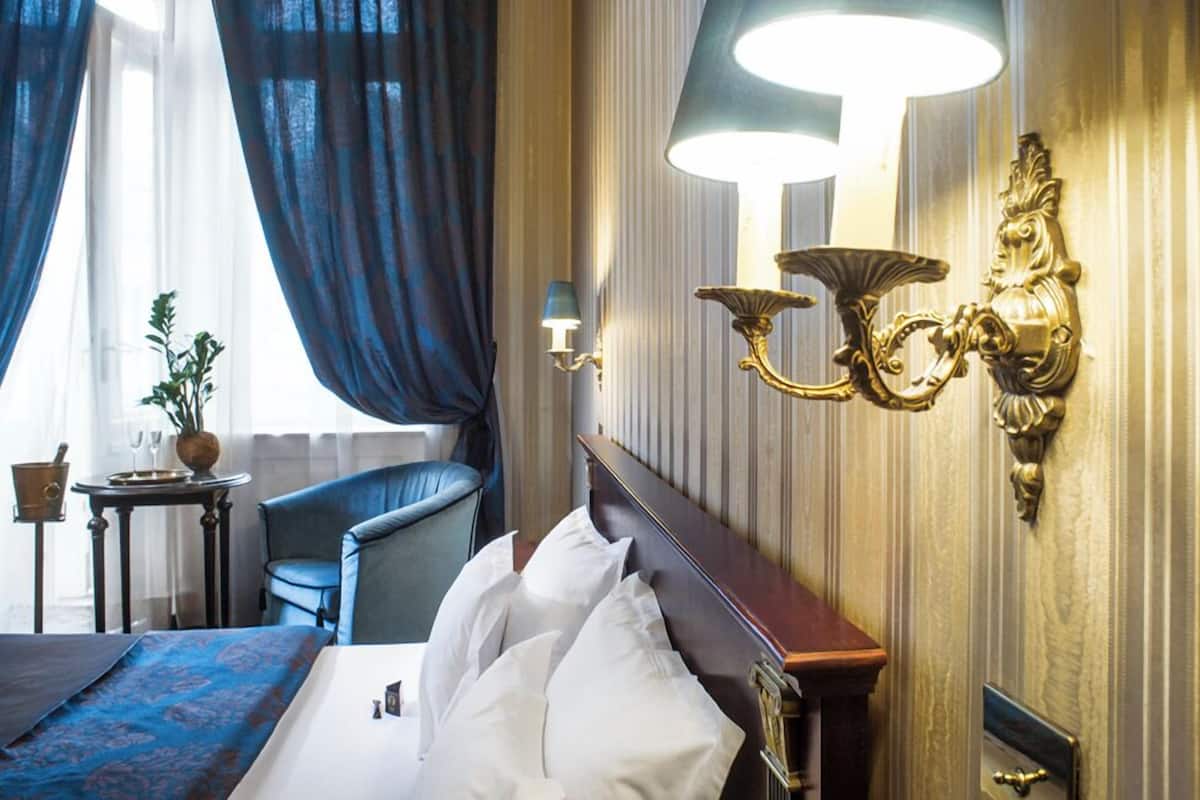 A hotel room with a bed, a chair, a lamp, and a small table with a plant.