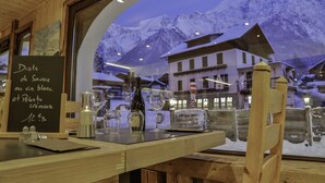 Een restaurant met uitzicht op besneeuwde bergen door een groot raam.