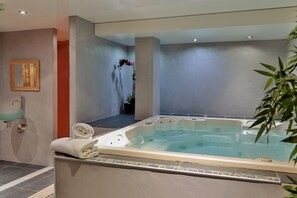 Relax in a spacious hot tub surrounded by a minimalist bathroom with a sink and mirror.