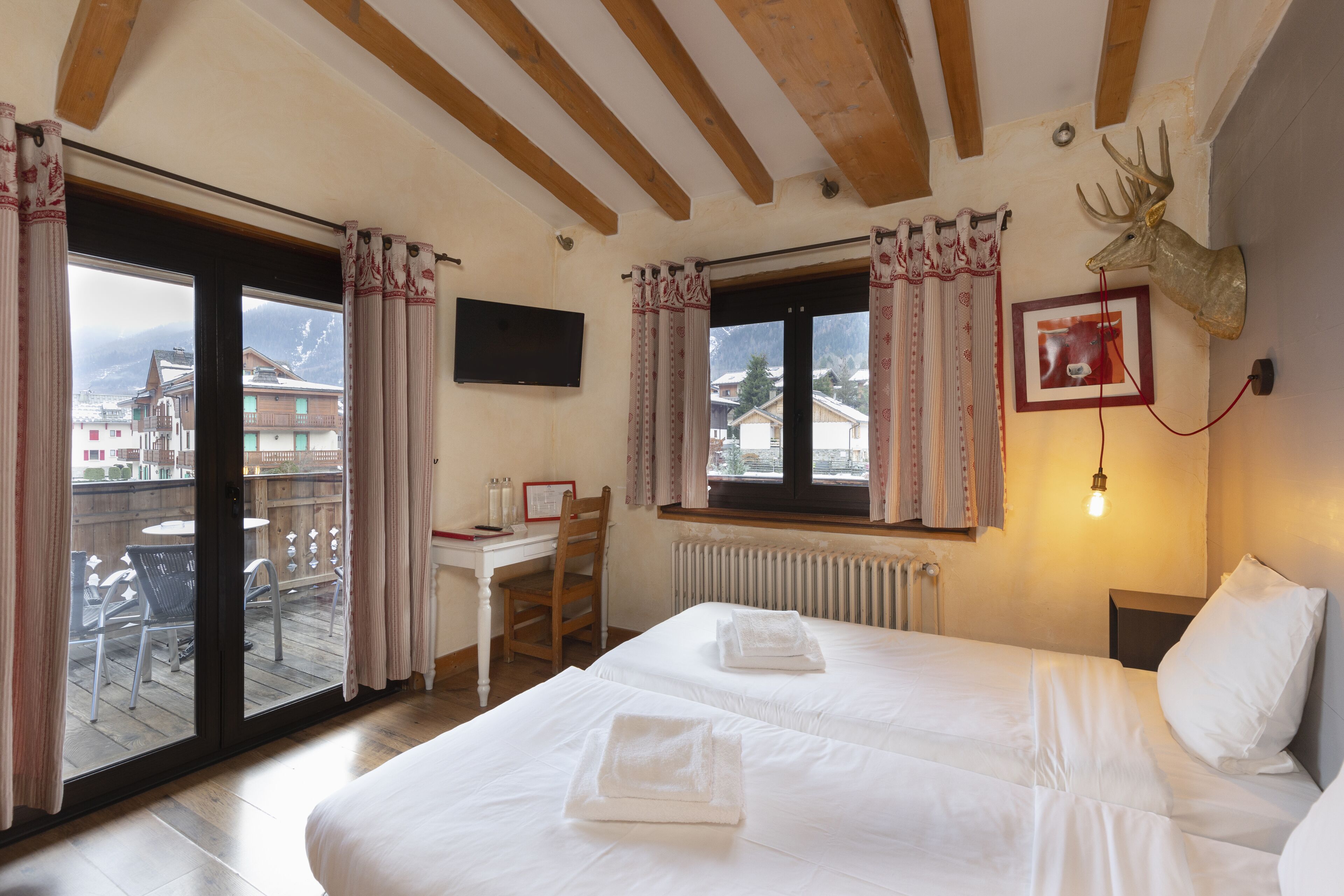 Habitación de hotel con dos camas, un escritorio y una silla.