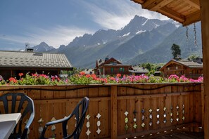 Enjoy breathtaking views of the surrounding mountains from this deck, featuring a table and chairs.