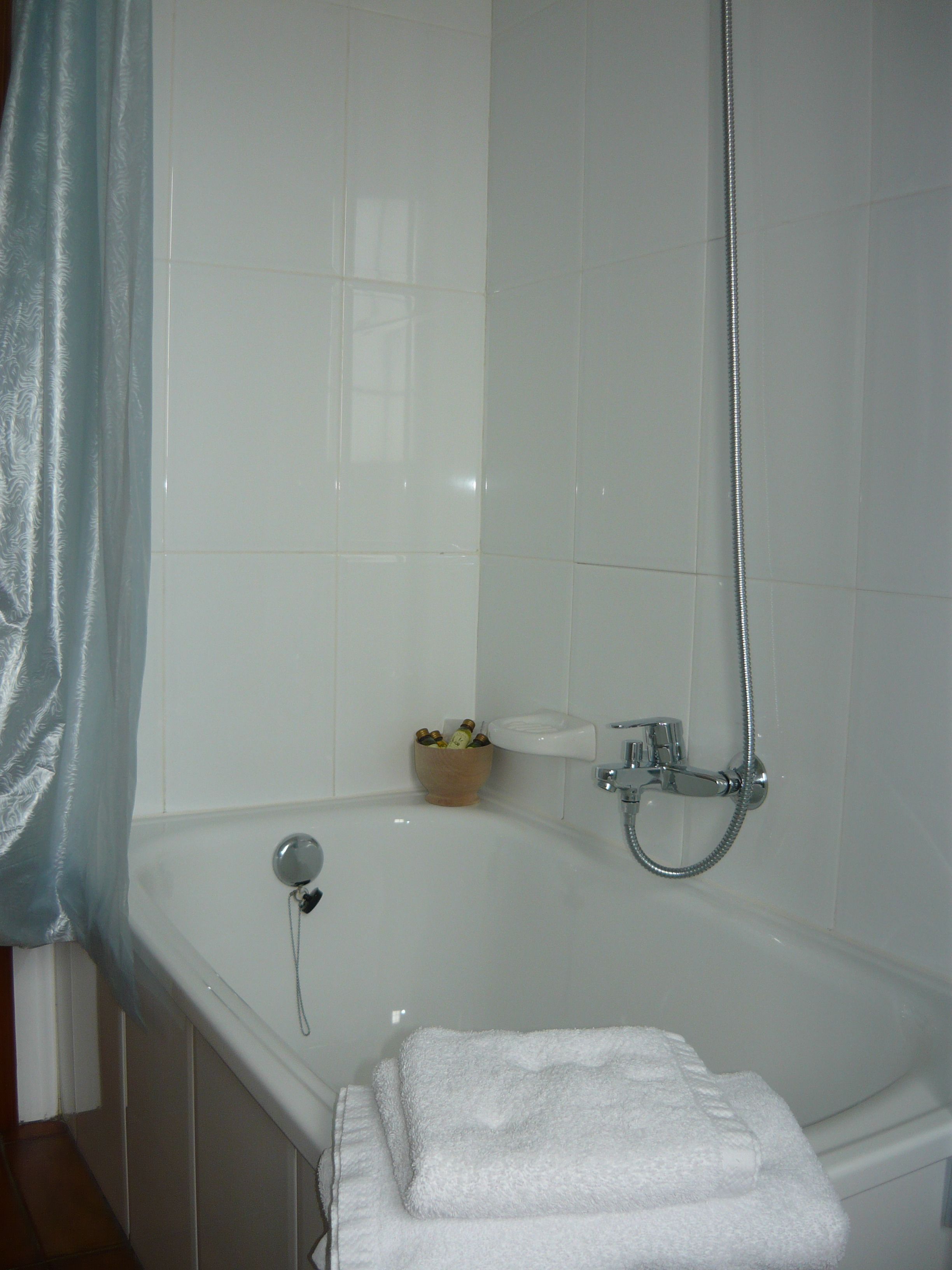A bathroom with a bathtub, a shower, and a small wooden bowl on the wall.