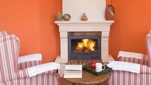 A cozy room with a fireplace, striped chairs, and a small table with a tray of items. - Turismo Rural Suquin (Navia)