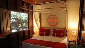 Ein Zimmer mit einem großen Bett, einem fensterbelaubten Fenster, einer Wanddekoration und zwei Nachttischlampen.