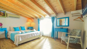 Un dormitorio con techo de madera, cama con ropa de cama azul, escritorio, silla y ventana con cortinas.