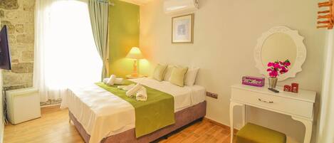 A bedroom with a bed, bedside table, lamp, air conditioning unit, and a small stool.
