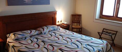 A bedroom with a bed, a nightstand, a chair, and a window.