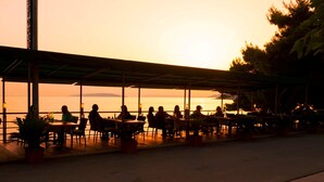 A seaside restaurant with outdoor seating, a covered area, and a view of the ocean.