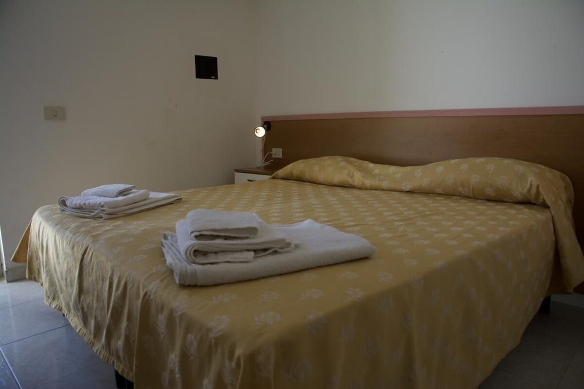 Un lit bien fait, avec une couvre-lit à motifs et des serviettes pliées posées sur le bord.