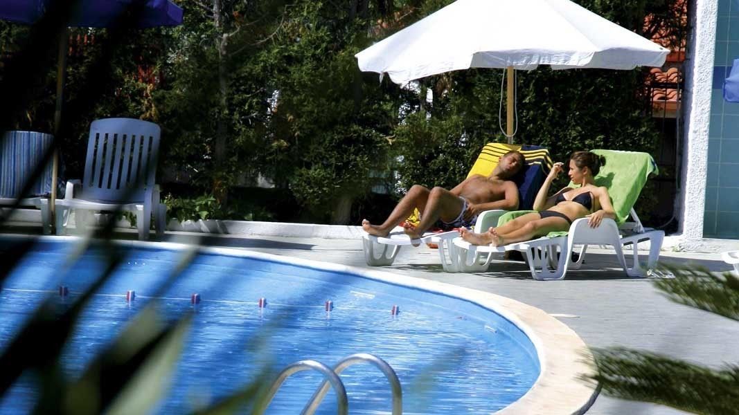 A pool area with lounge chairs and umbrellas.