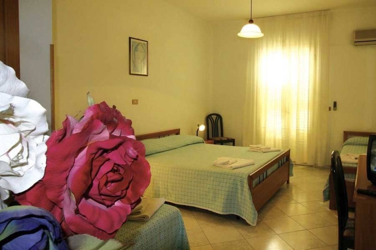 Habitació d'hotel amb un llit, televisió, una cadira i un ampli arranjament floral.