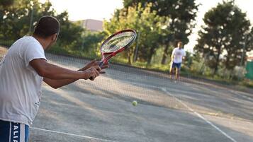 Un court de tennis avec un filet au milieu, une balle de tennis en l’air et une personne tenant une raquette de tennis.