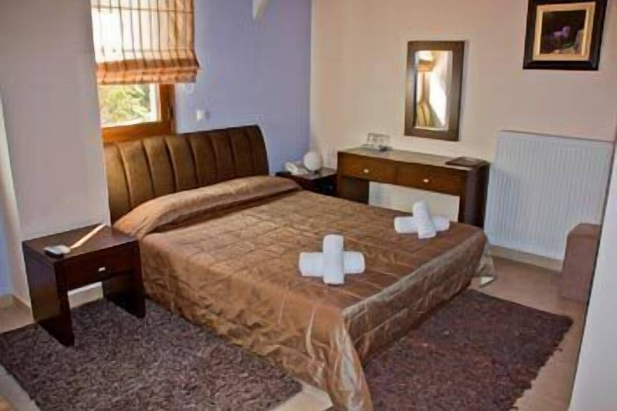 A bedroom with a bed, nightstands, a dresser, a mirror, and a window with blinds.