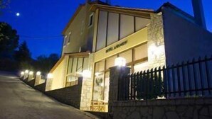 A two-story building with a stone facade, a visible entrance, and a gated driveway. - Ahilion (Kalavrita)