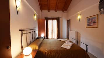 Camera da letto con soffitto in legno, un letto con testiera, lampade sui comodini, un termosifone e un quadro appeso al muro.