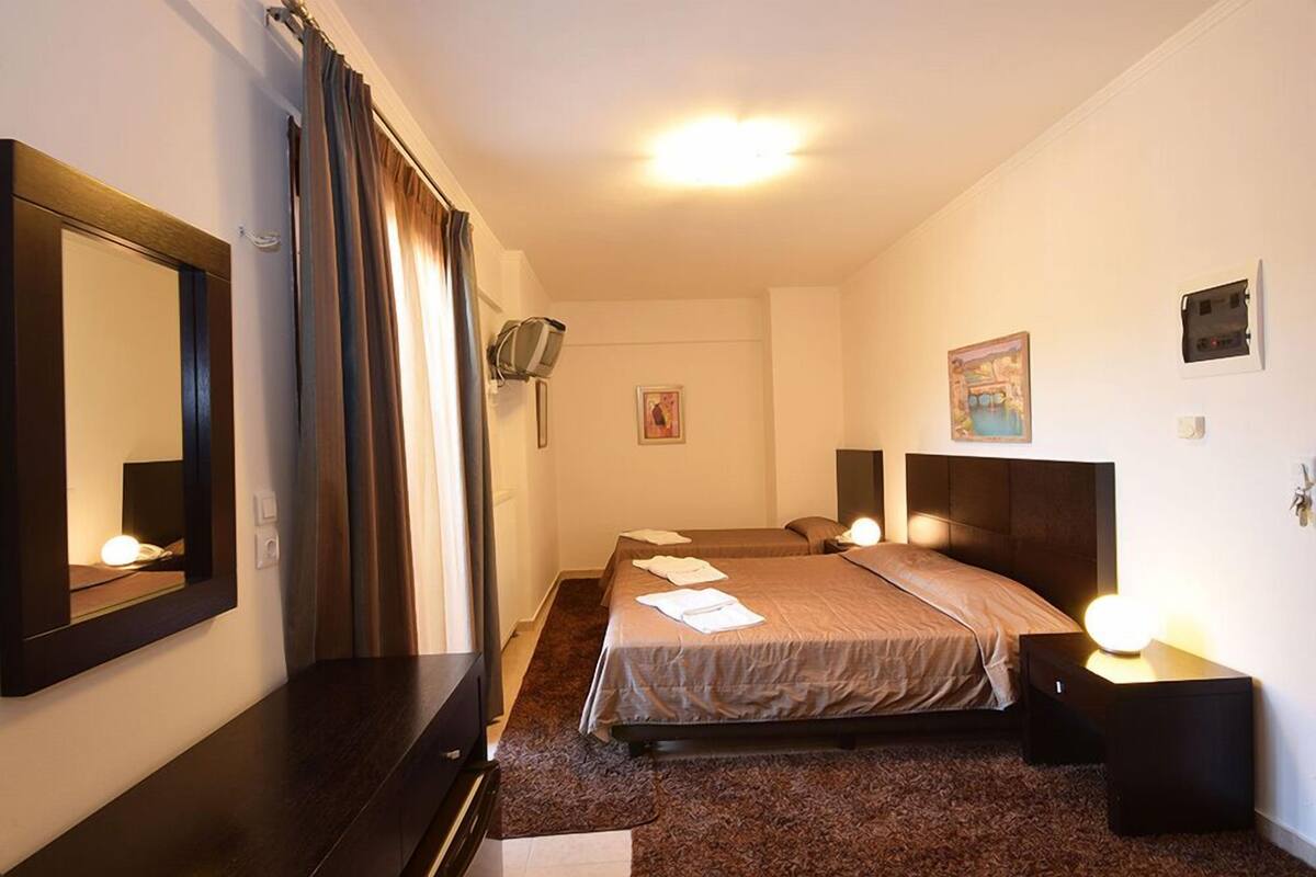 A hotel room with a large bed, a bedside table with a lamp, a mirror, and a picture on the wall.