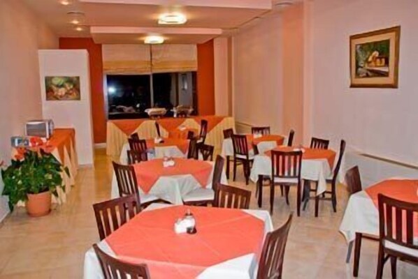 Un comedor con mesas cubiertas de manteles rojos, sillas de madera y una planta en maceta.