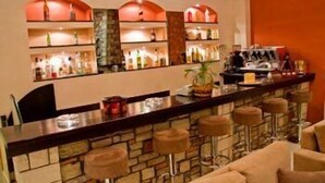 A bar area with a stone counter, stools, and shelves with bottles. - Ahilion (Kalavrita)