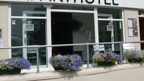 Un APARTHOTEL doté de grandes fenêtres, d’une enseigne « BIENVENUE » et de jardinières à l’extérieur.
