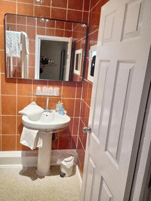 A bathroom with a white sink, a mirror, and a door. - Aparthotel Blackpool (Blackpool)