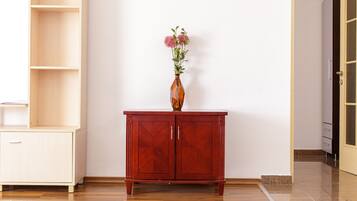 A wooden cabinet with two doors and a vase with flowers on top.