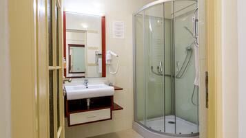A bathroom with a glass-enclosed shower, a sink with a mirror, and a towel rack.