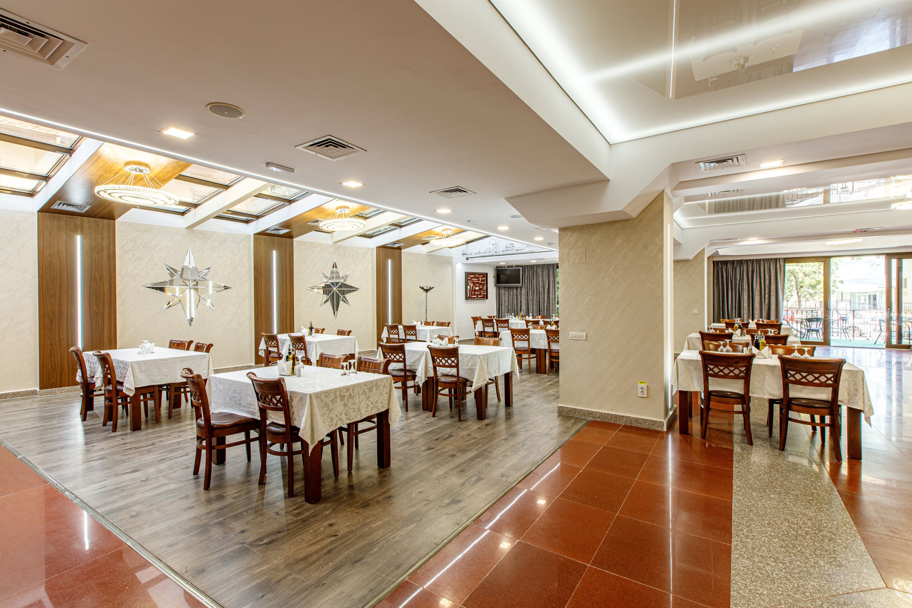 A spacious dining area with multiple tables and chairs, high ceilings with skylights, and a modern design.