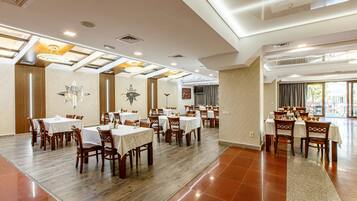 A spacious dining area with multiple tables and chairs, high ceilings with skylights, and a modern design.