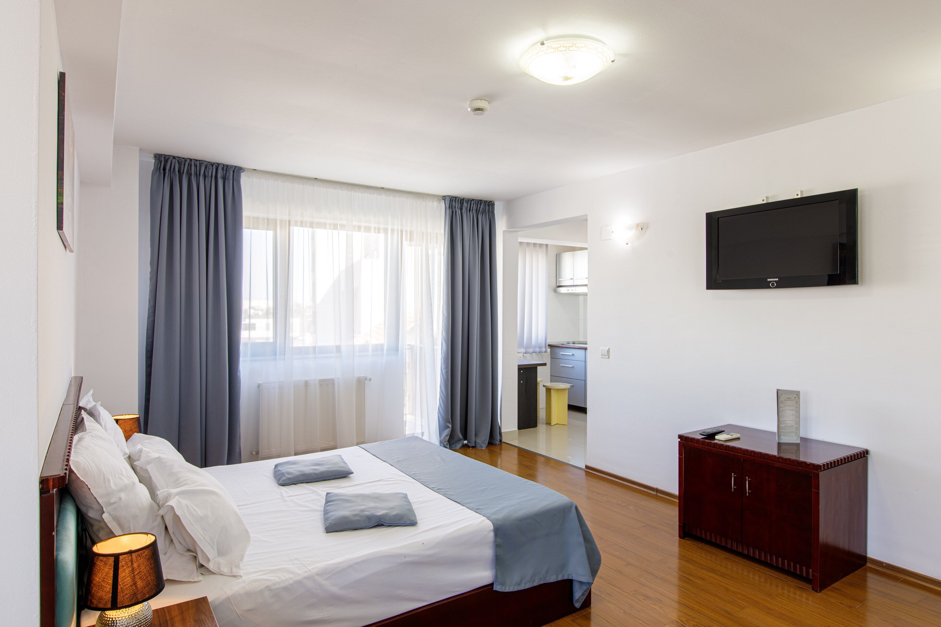 Camera d'albergo con un letto, una scrivania, una televisione e un bagno visibile attraverso una porta aperta.