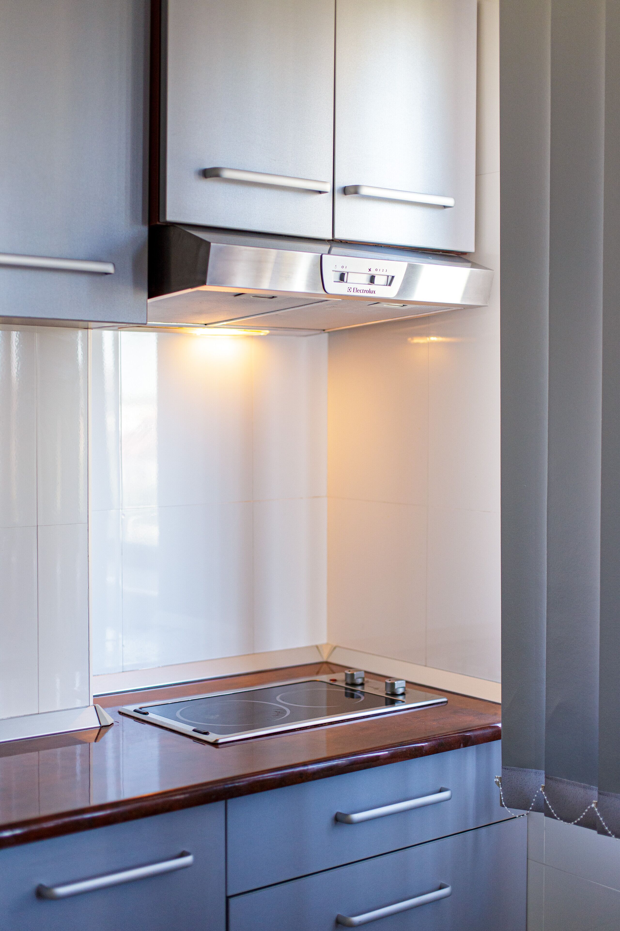 Una cocina con campana de acero inoxidable, horno empotrado y encimera de madera.