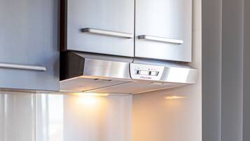 Una cocina con campana de acero inoxidable, horno empotrado y encimera de madera.