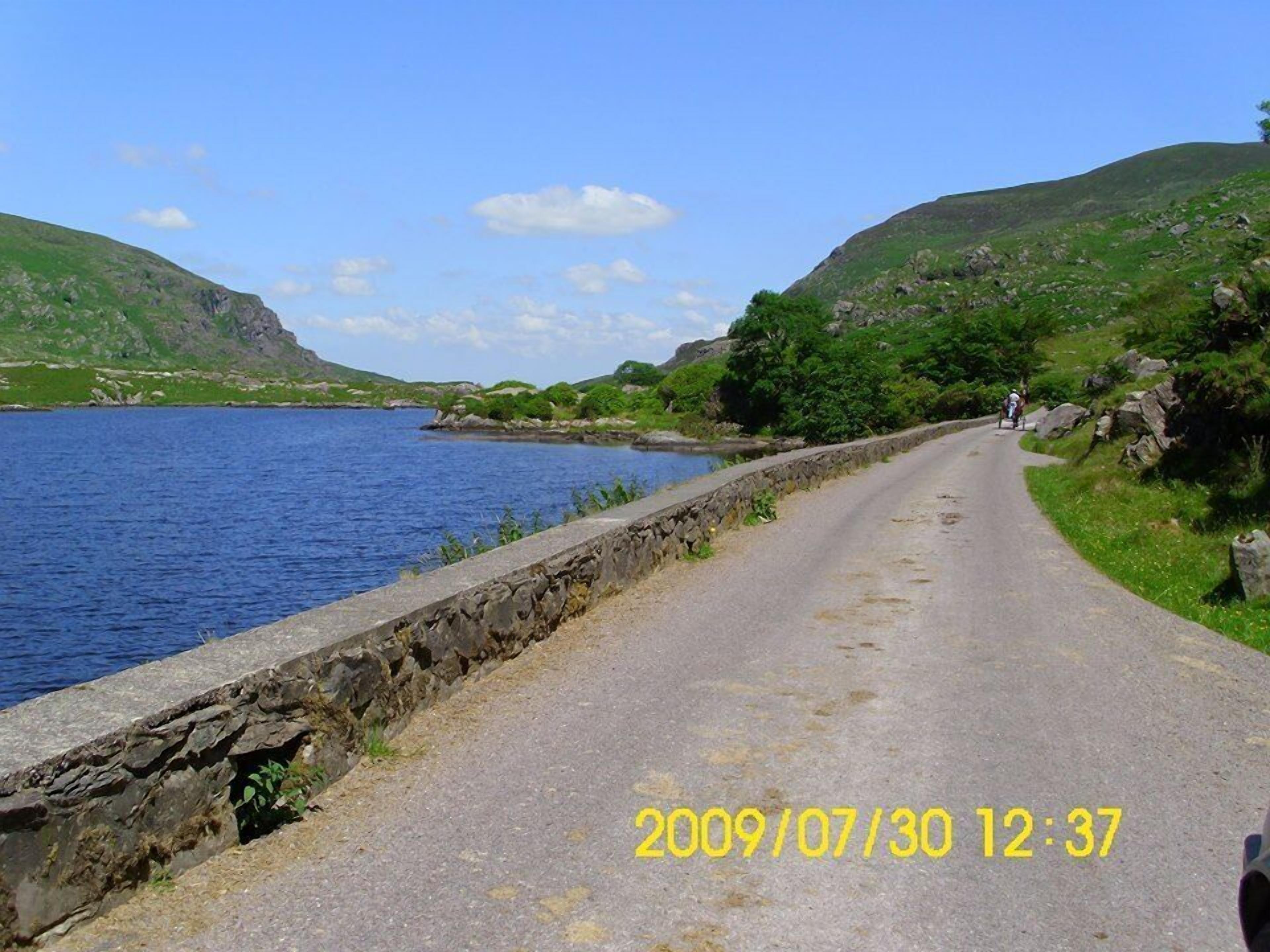 A coastal road with a stone wall on one side and a body of water on the other.