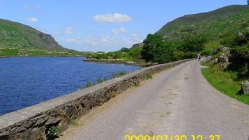 A coastal road with a stone wall on one side and a body of water on the other.