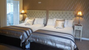 A hotel room with two beds, a large window, and a bathroom visible through the door.