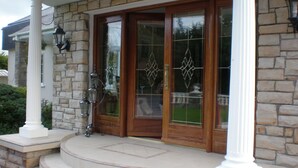 A stone facade with a wooden front door, a set of steps leading up to the entrance, and a white column on the left.