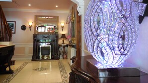 A grand foyer with a chandelier, a fireplace, and a decorative mirror.