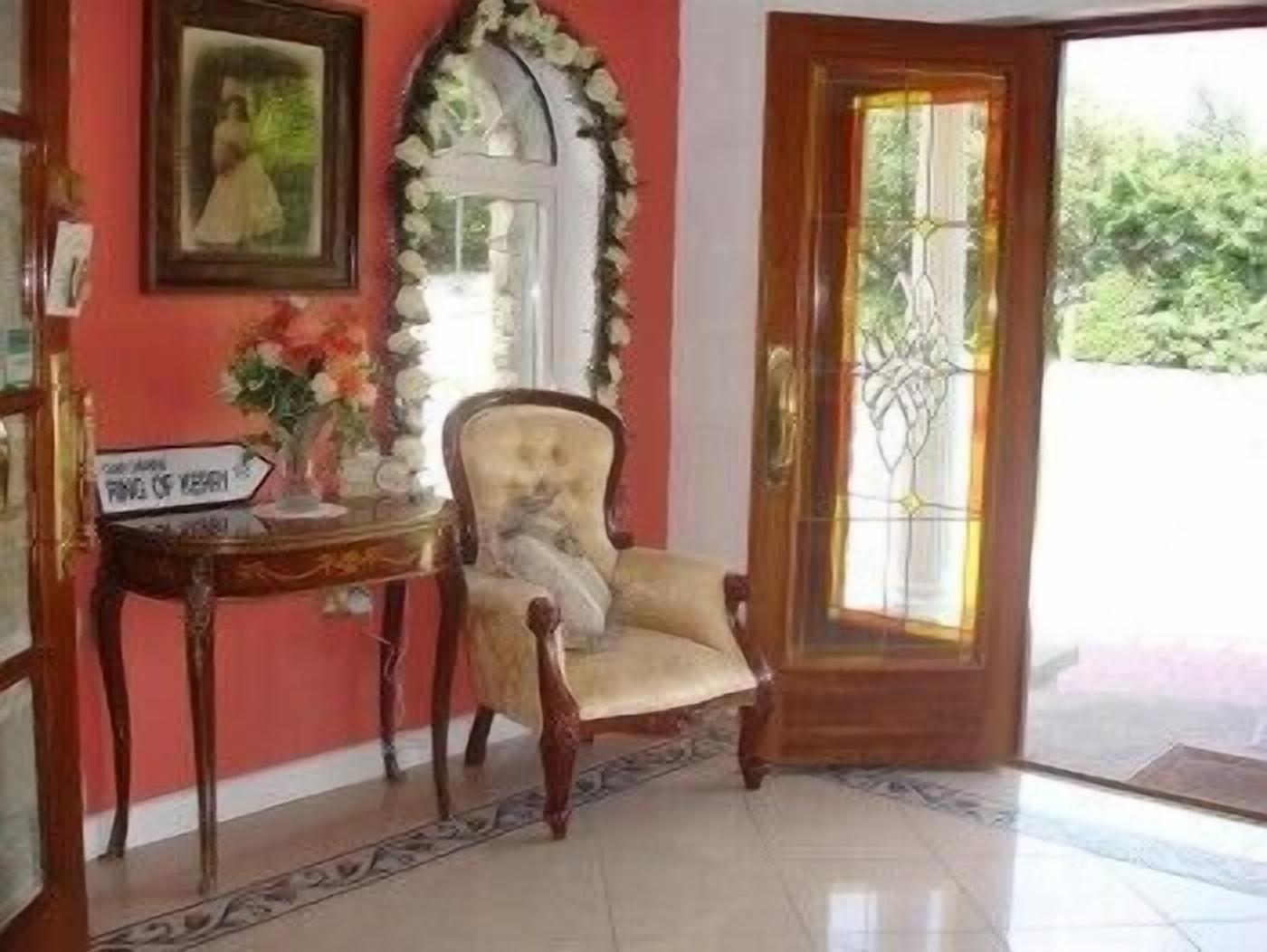 Une pièce avec une porte en bois, un tableau encadré au mur, une chaise et une petite table sur laquelle est posé un panneau.