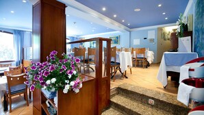 A hotel dining area with wooden chairs, tables, and a staircase leading to an upper level. - Hotel Montane (Arinsal)