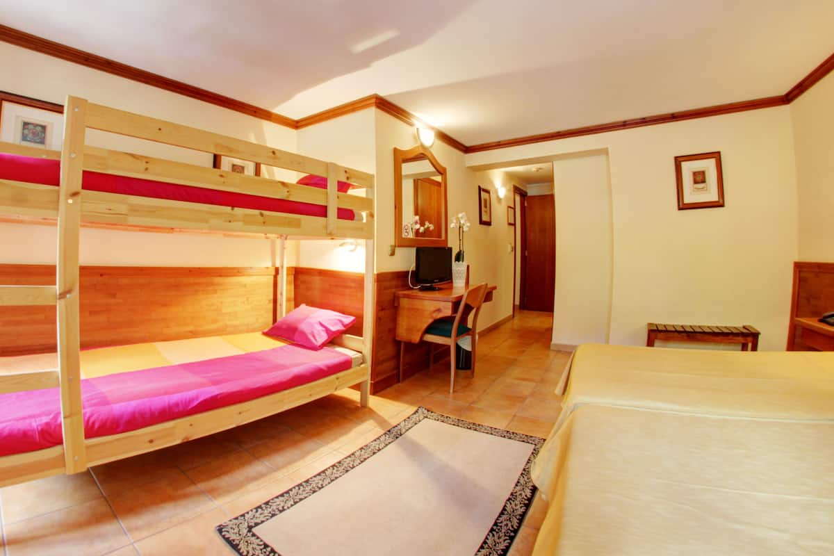 A room with bunk beds, a desk, and a chair.