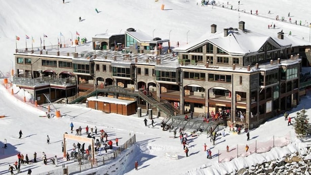 A multi-story hotel with a ski lift in the background, surrounded by snow. - Hotel Montane (Arinsal)