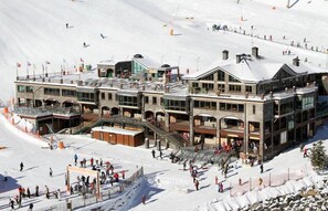 A multi-story hotel with a ski lift in the background, surrounded by snow. - Hotel Montane (Arinsal)