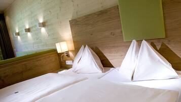 Habitación de hotel con cabecera de madera, pared de acento verde y cama con ropa de cama y almohadas blancas.