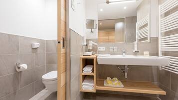 Un baño moderno con inodoro, lavamanos y estantes empotrados para toallas.